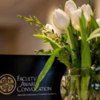 Award booklet next to a vase of white flowers